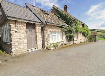 A wisteria-clad, stone-built Withypool holiday cottage with oak front door.