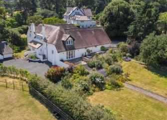 Aerial view of a large holiday cottage on the Somerset coast surrounded by gardens.
