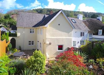 Exterior of an East Devon coastal cottage with a patio and a well-kept garden.