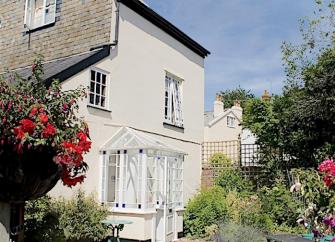 Exterior of a luxury Sidmouth holiday cottage surrounded by beautiful flower-filled gardens.
