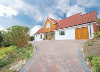 A large modern chalet bungalow is approached by a spacious block-paved drive.