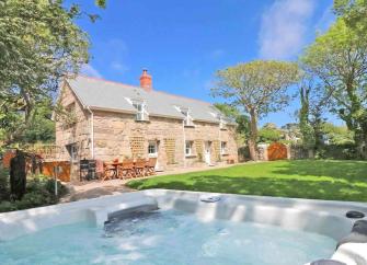 Large, stone-built Cornish cottage overlooks a garden with a hot tub.