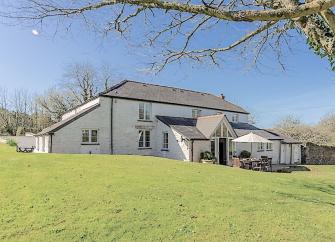 An extended farmhouse holiday cottage overlooks an expansive lawn.