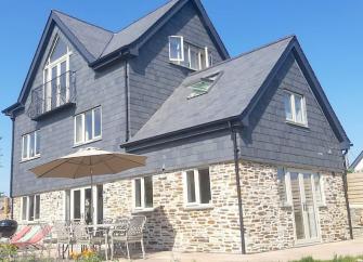 A large, 3-storey detached house built of stone with a 1st floor clad in slates.