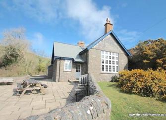 A converted stone-built, remote Exmoor schoolhouse with a lawn and large patio.