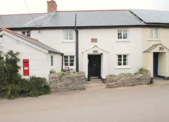 Double-fronted cottage exterior overlooks a quiet village street.