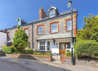 A stone-built house with loft conversion overlooks a low-walled front courtyard.