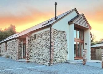 A Devon barn conversion with a deck at sunset.