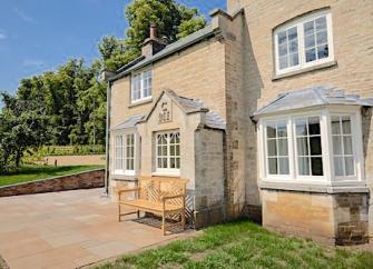 Exterior of a former Head Gardener's estate house with bay windows, a front patio and lawn