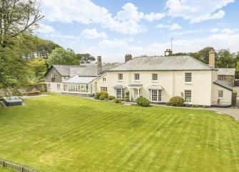 Exterior of a 2-storey country house on Exmoor overlooking a large lawn with a hot tub.