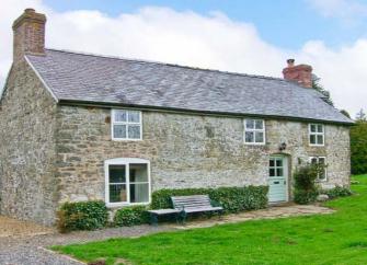 A long, stone-built Shropshire cottage surrounded by a large hedge-lined lawn
