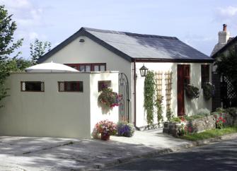 Single storey exterior of a white-rendered bungalow with hanging flower baskets.