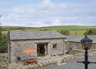 Front exterior of a tone built barn conversion in Cumbria with a small, pave courtyard.