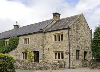 Large LEyburn holiday cottage built with local stone and surrounded by a low stone wall.