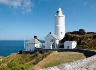 A lighthouse complex in a clifftop location with the sea in the background.