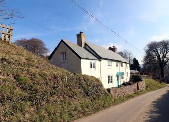 An Exmoor Longhouse overlooks a quiet, steep-banked country lane