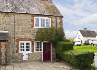 A semii-detached Dorset cottage overlooks a paved front courtyard for parking.