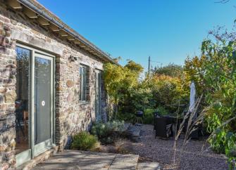 A single storey barn conversion with Frenchwindos and a mature garden of shrubs and small trees.