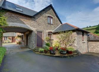 A coastal holiday cottage with a large arch to a flower-filled courtyard in South Devon.