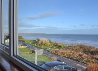 Beach lawns and the sea are viewed from the window of a holiday cottage opposite. 
