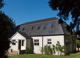 Extrior of a 2-storey coach house conversion with covered porch and garden lawn