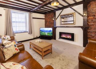An oak beamed lounge with woodburner, wide-screen TV and a comfy sofa.