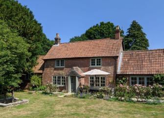 A stone-built Dorset cottage overlooks a lawn and rose beds.