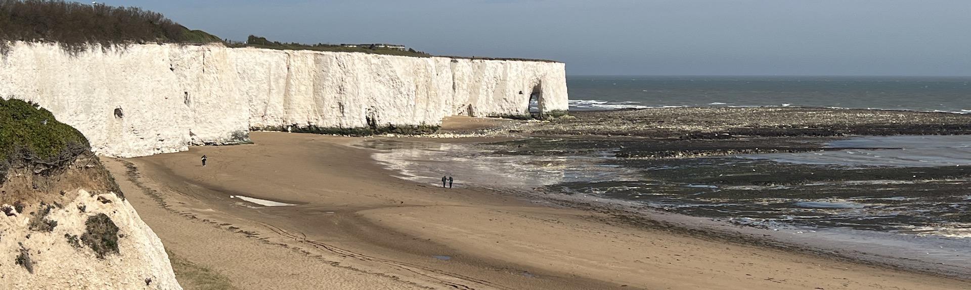 white cliffs at Broadstairs tower above a sandy beach at low tide on a clear summer's day.