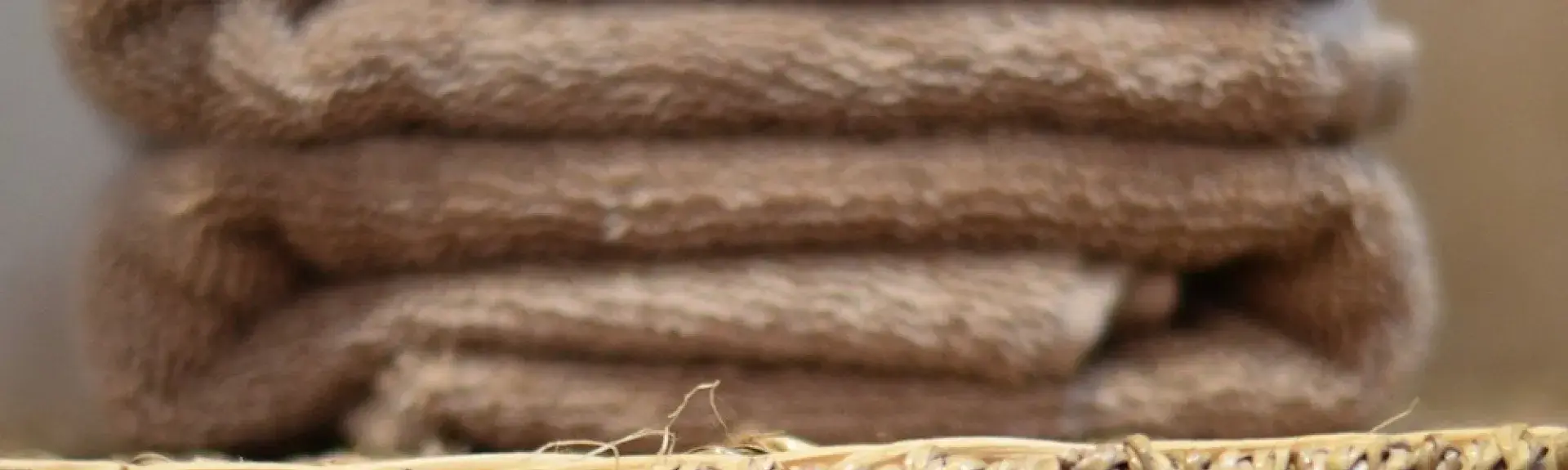 A neatly folded luxury towel on top of a wicker basket