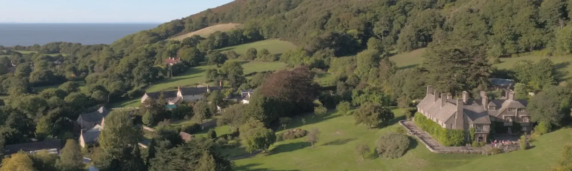 A cluster of village cottage roofs nestle beneath a moorland hill.