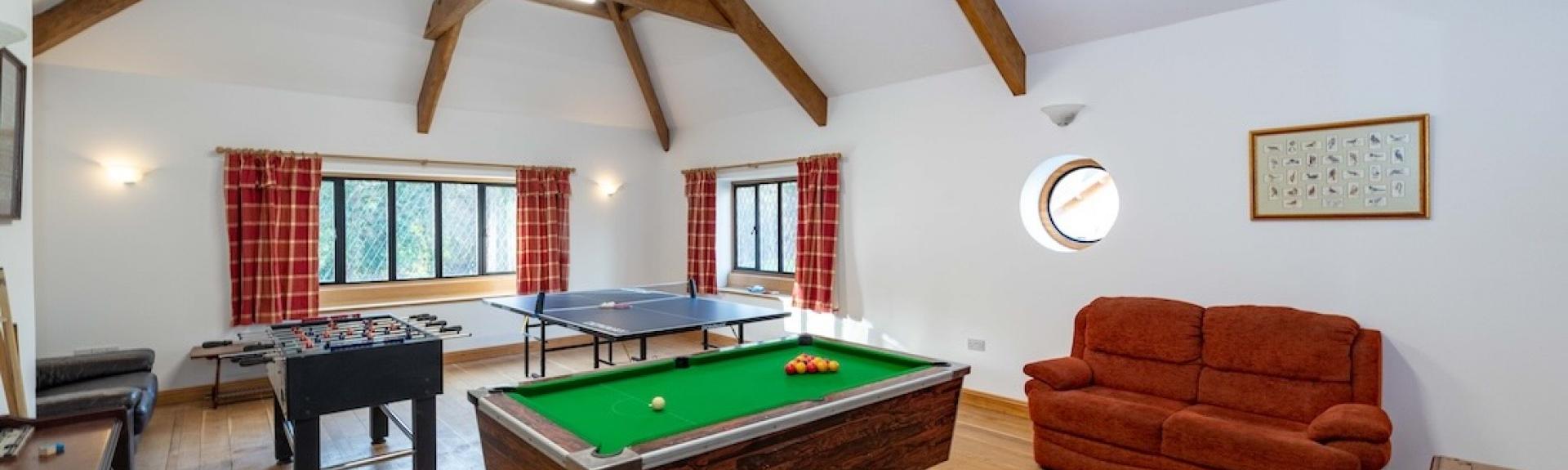 A holiday cottage games room with table football, table tennis an pool tables. in a games room.