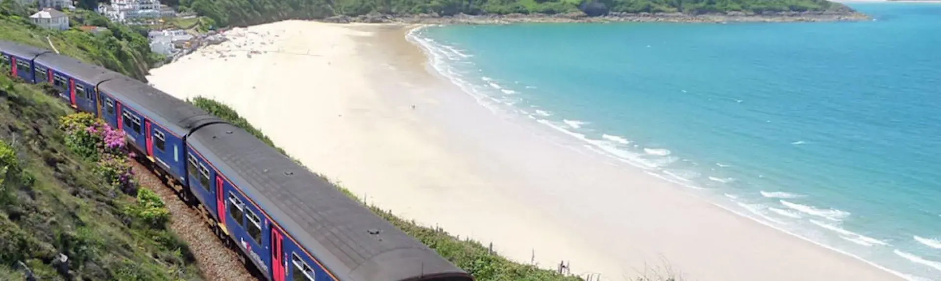 A train glides along a track overlooking a large sandy beach near St.Ives. Photo credit: Mark Lynham