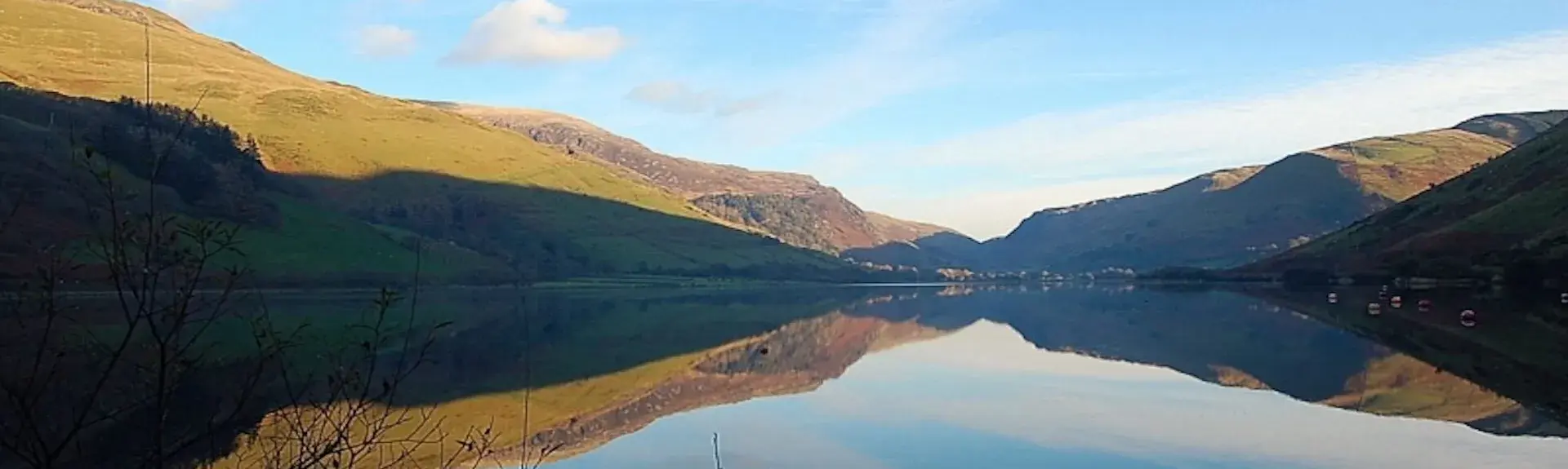 Calm waters reflect the land in an autumnal view of a reservoir at sunset