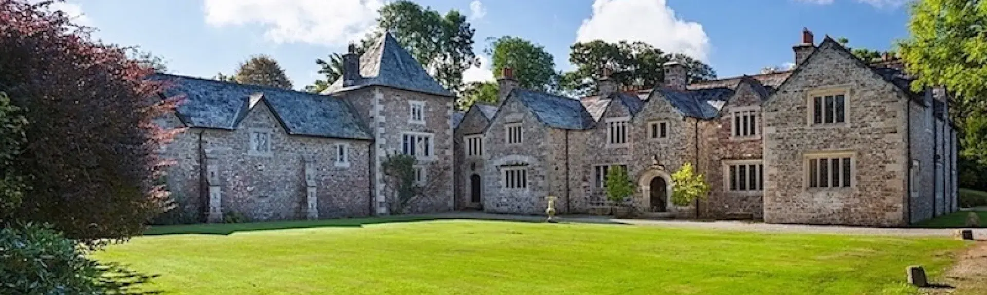 exterior of a historic Dartmoor manor house overlooking a large lawn