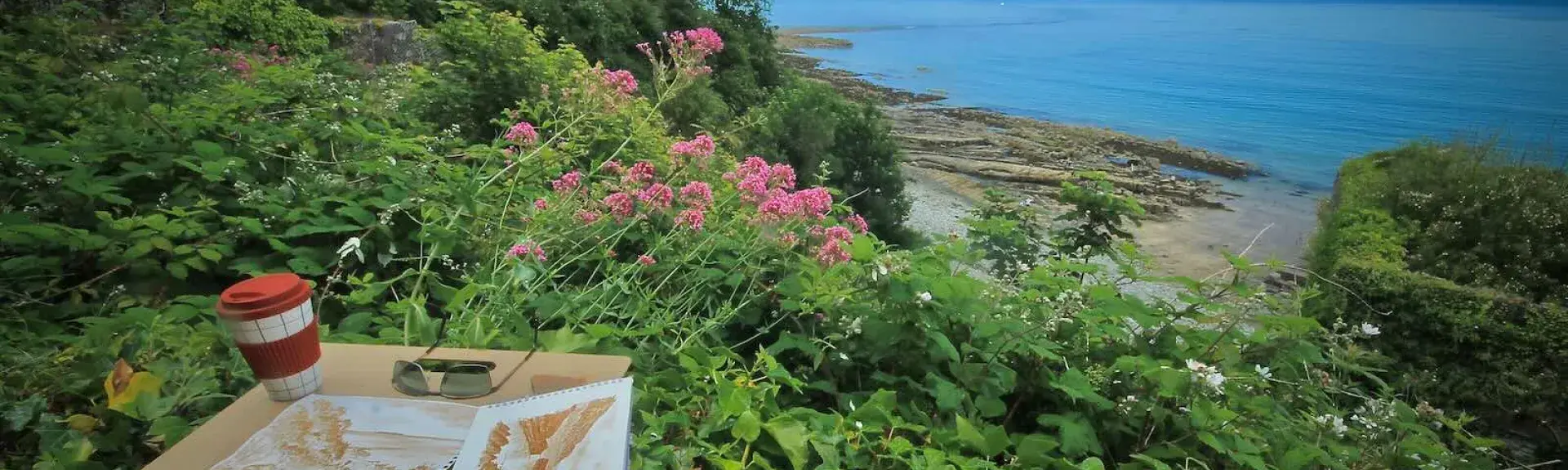 water colour paintings resting on an ivy-covered stone wall with a  sea view in the background