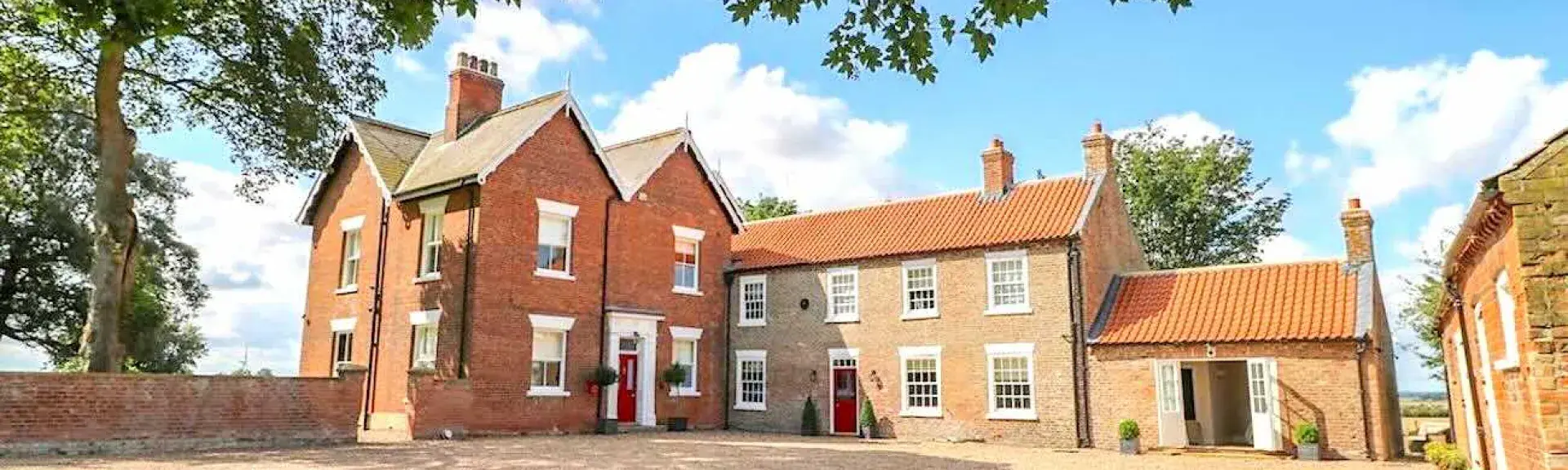 Exterior of a large, brick-built manor house overlooking a spacious courtyard.