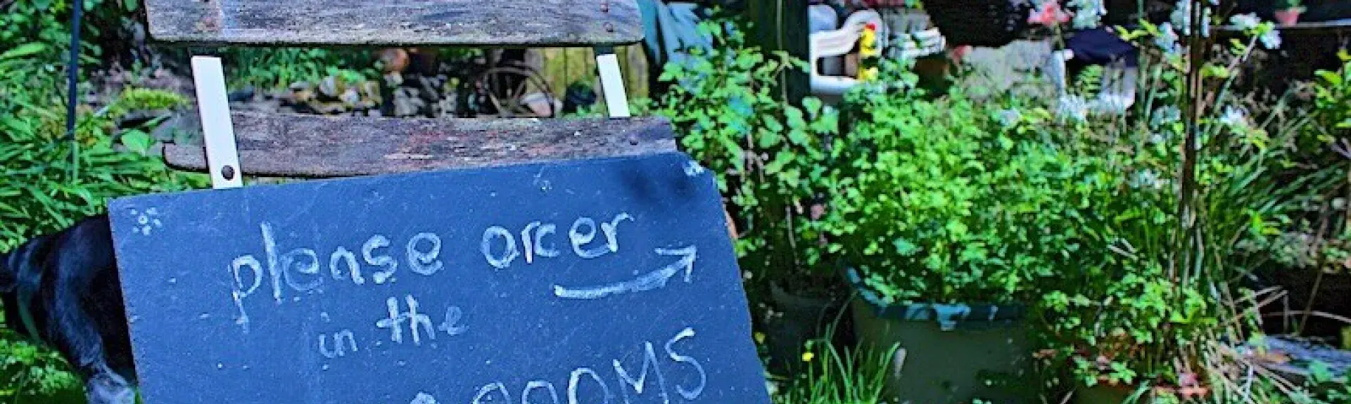 A blackboard sign  perched on a wooden chair welcoming customers to an Exmoor Tearoom