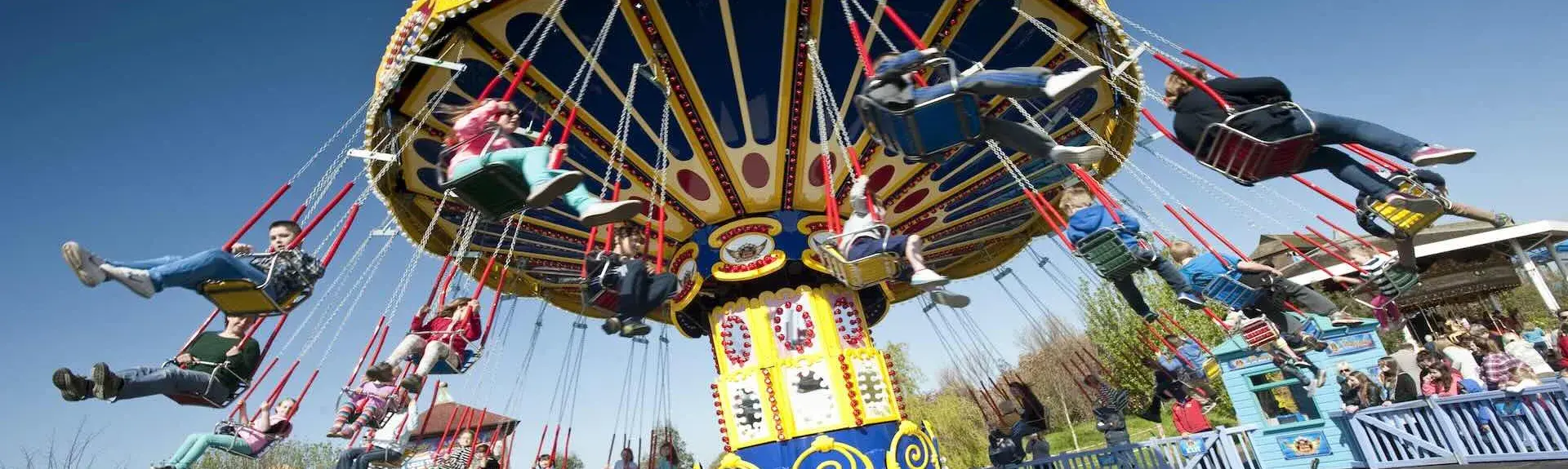 A colourful chair-o-plane, a vintage fairground ride spinning  round people in chairs.