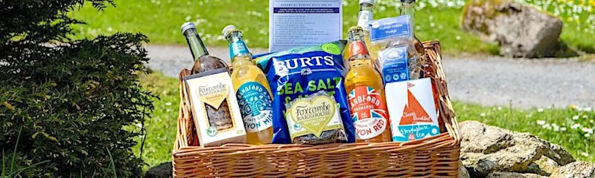 A welcome pack of food and drink in a wicker basket on a rocky garden cairn.