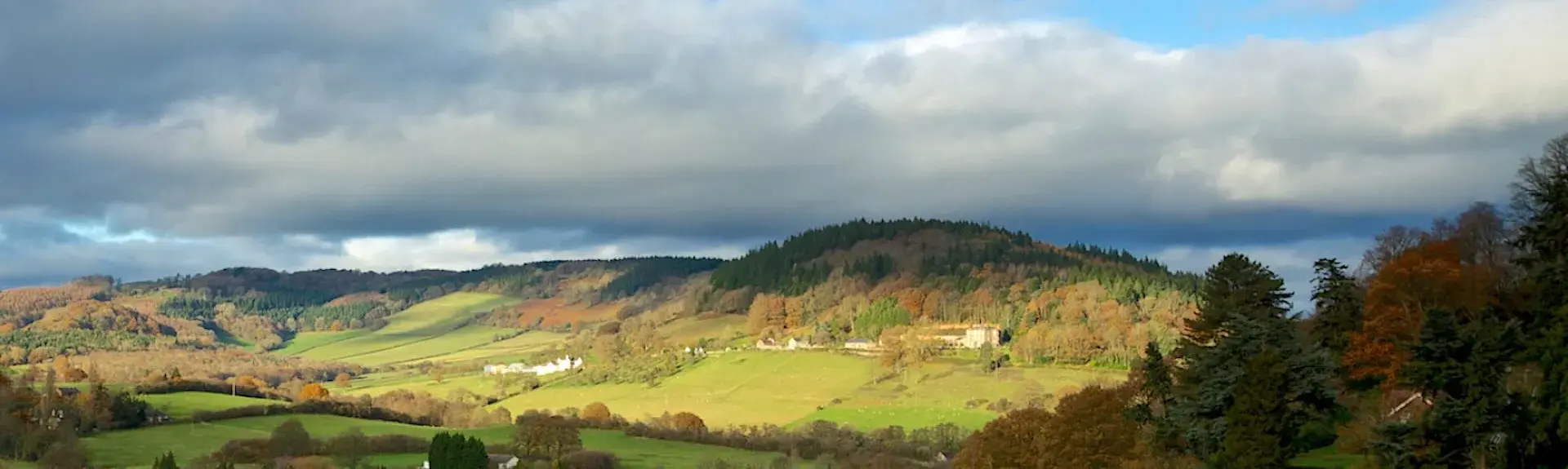 A landscape view of the Wye Valley at dusk with trees and open fields.