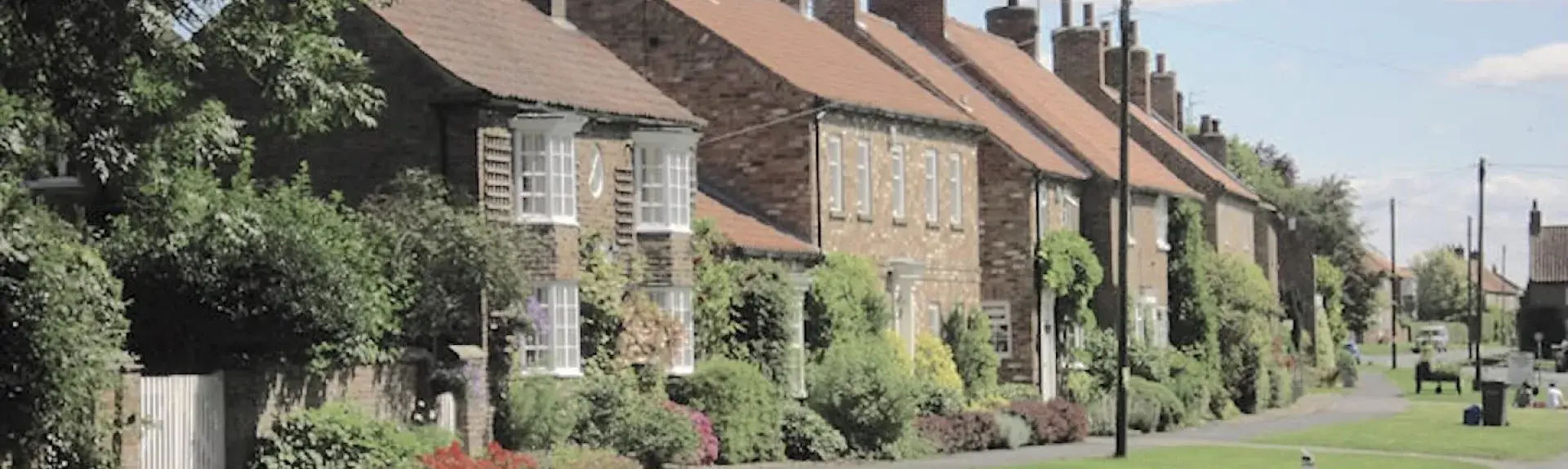 A row of stone-built cottages overlook a village green in Sutton-on-the-Forest.