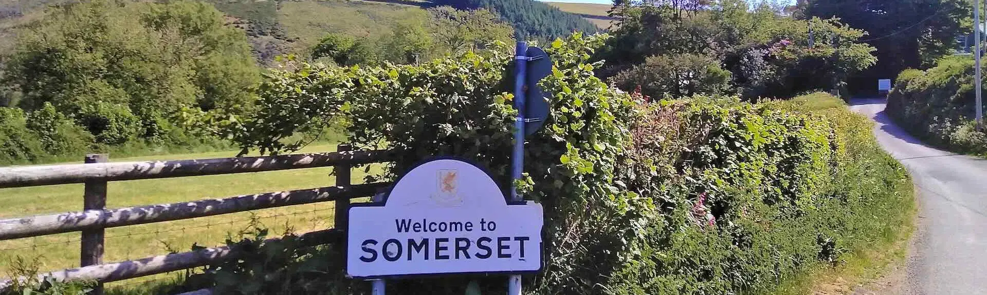 A 'Welcome to Somerset' sign on a quiet, winding country lane.