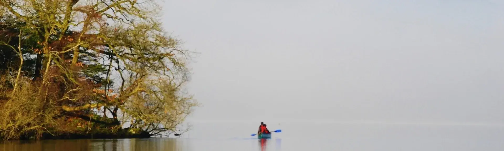 A holiday cottage overlooks a large lake in front of tall Lake District Fells.