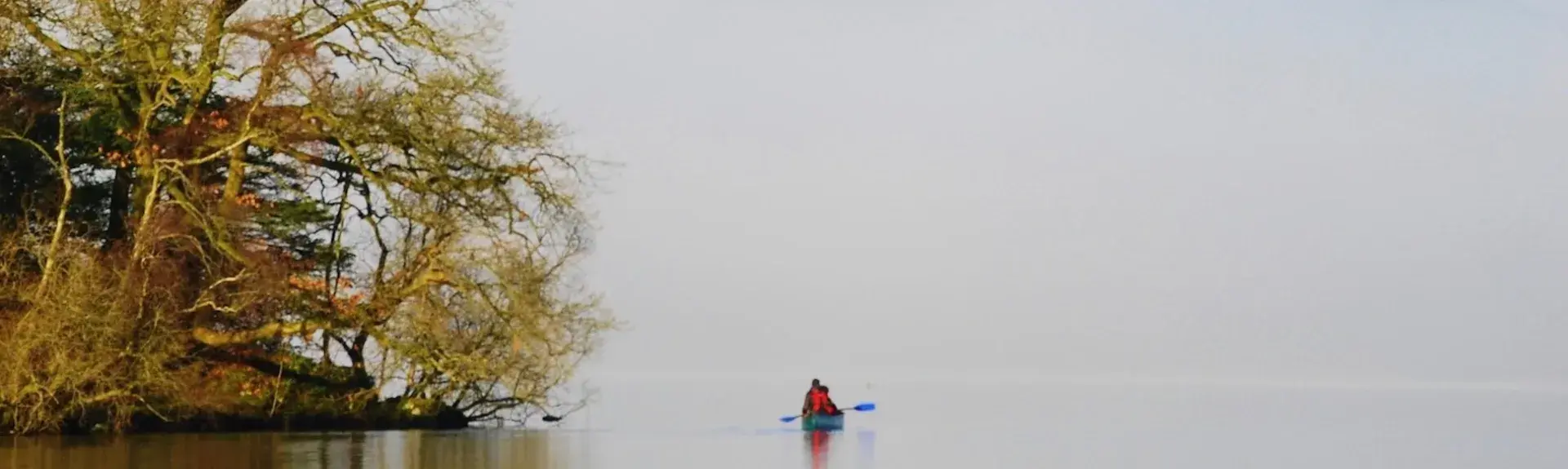 A lone kayaker paddles past an Island on a wintery day on Lake Windermere.