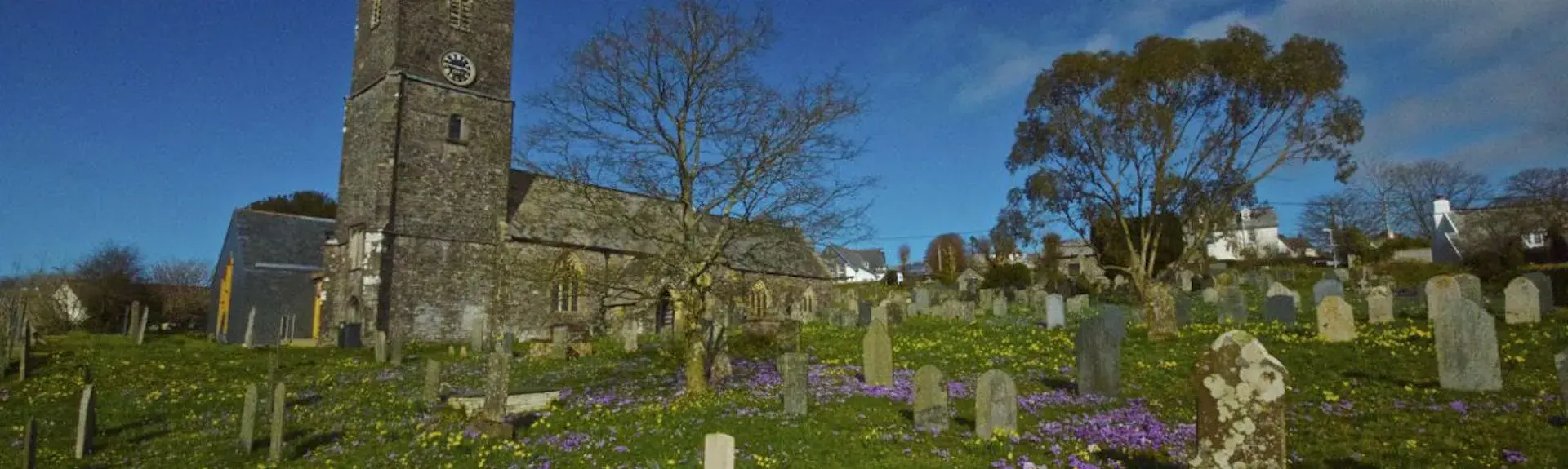 A North Devon hilltop church overlooks a grave yard filled with daffodil and crocus blooms.