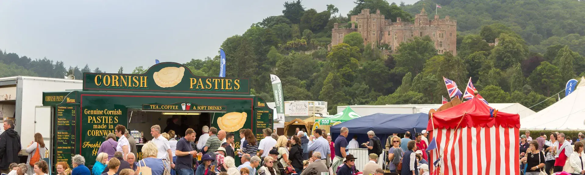 Families at Dunster Show watch a Punch and Judy show with Dunster Castle in the background