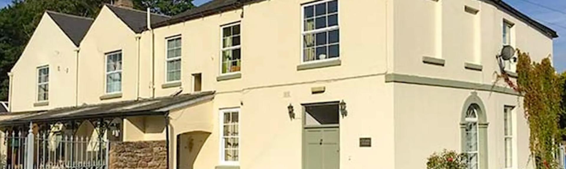 A large, rendered Hereford holiday home with large sash windows overlooks a spacious paved courtyard.