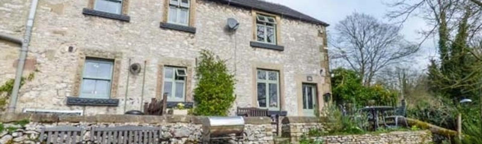 Large stone-built rural cottage exterior with a spacious lawn.
