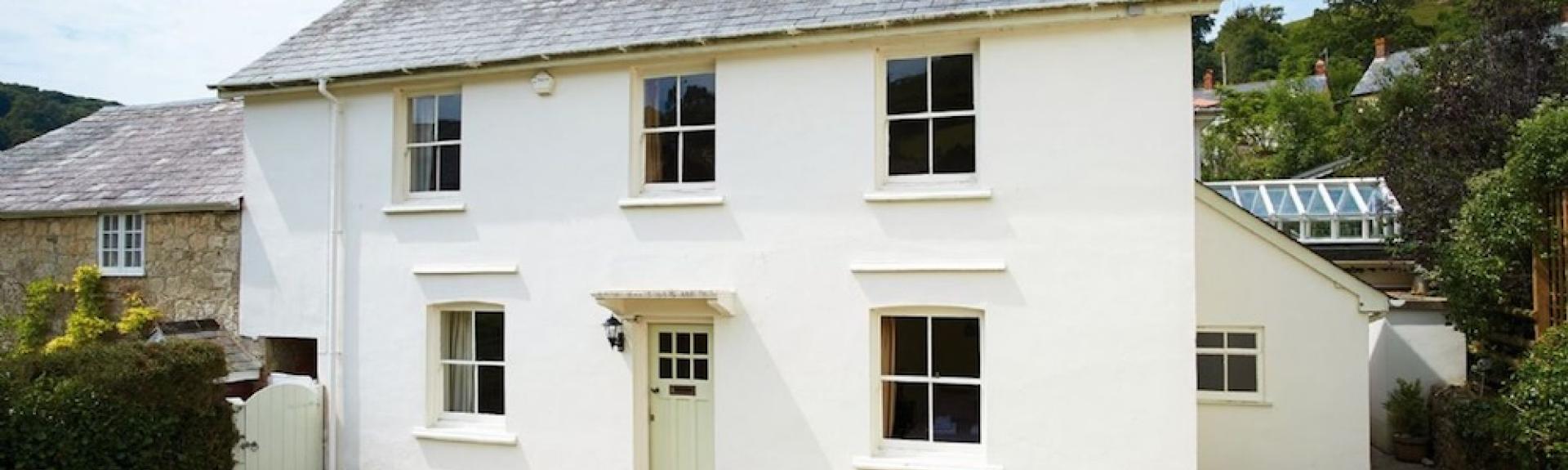 A double-fronted East Devon holiday cottage in front of a secure lawned garden.