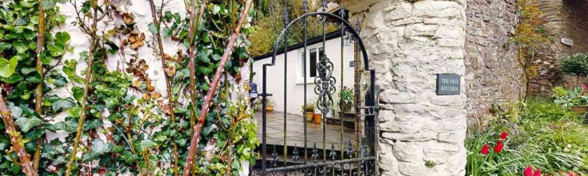 An arch in a wall leads to a courtyard of an Exmoor holiday cottage.